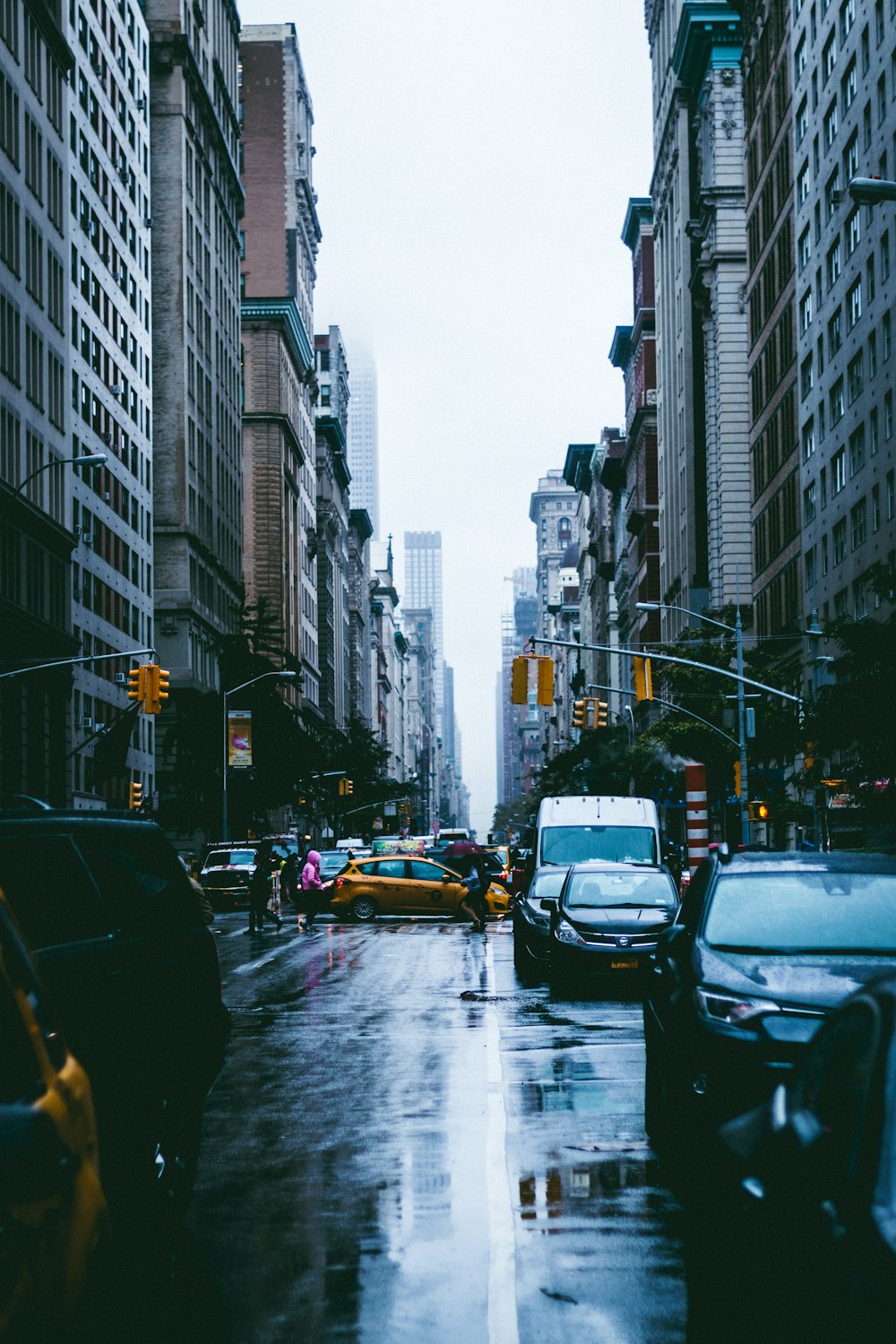 cars parked on asphalt road between concrete buildings