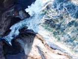 Dynamic aerial footage of a coastal cliff with waves crashing below.
