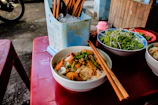 An elegant table setting with chopsticks and a steaming bowl of noodle soup.