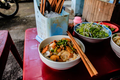 An elegant table setting with chopsticks and a steaming bowl of noodle soup.