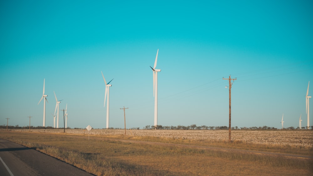 white windmills near asphalt road