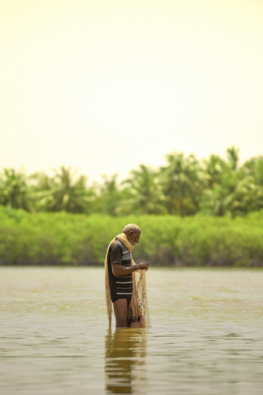 man holding fish net standing on body of water