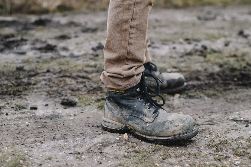 土の小道に立つ黒い作業靴を履いた人