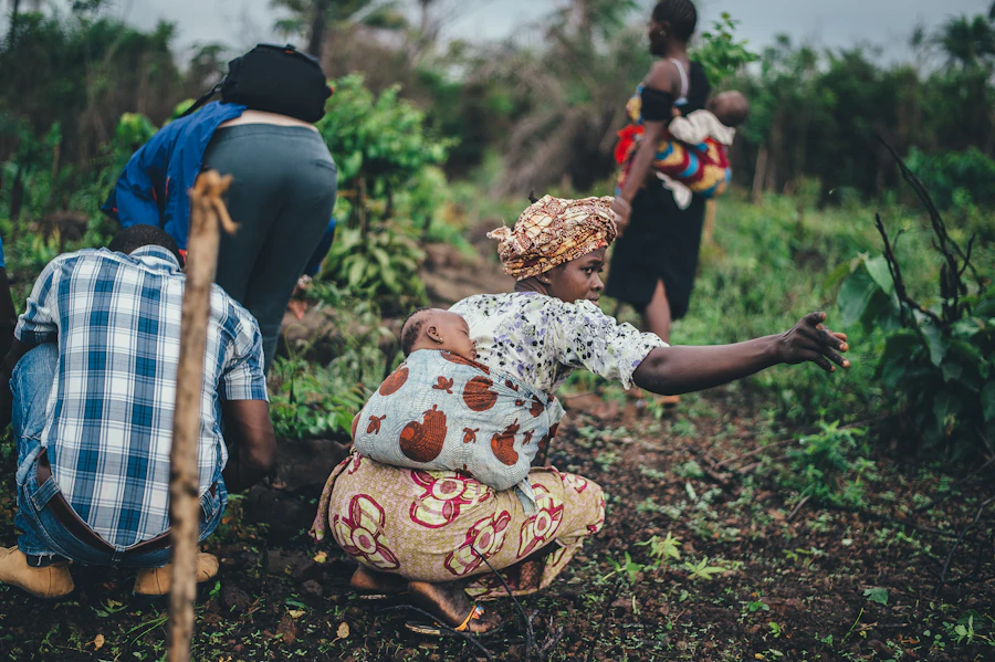 A Ugandan woman carrying a child on her back while working the land