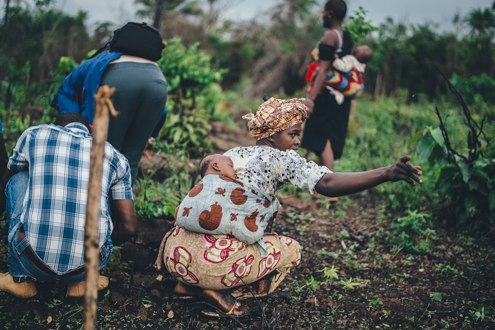 woman carrying toddler at back while planting