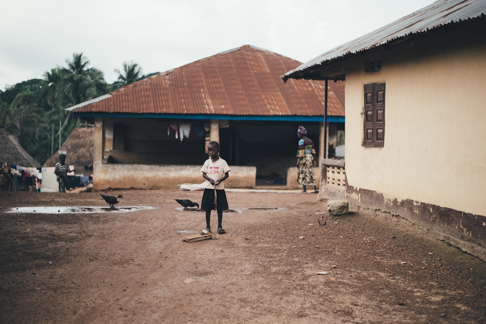 boy standing while holding wooden stick