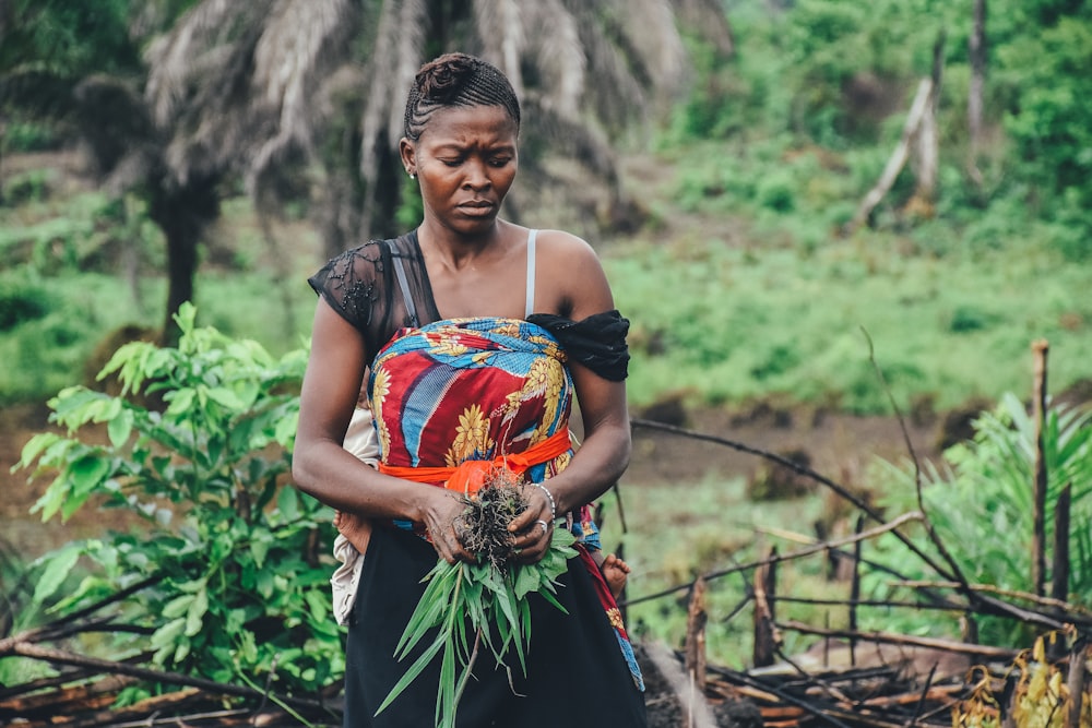 woman carrying green leafed plant in mountain