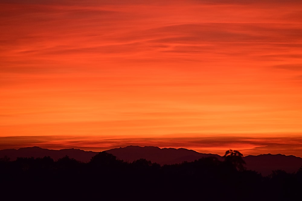 silhouette of mountain under orange sky
