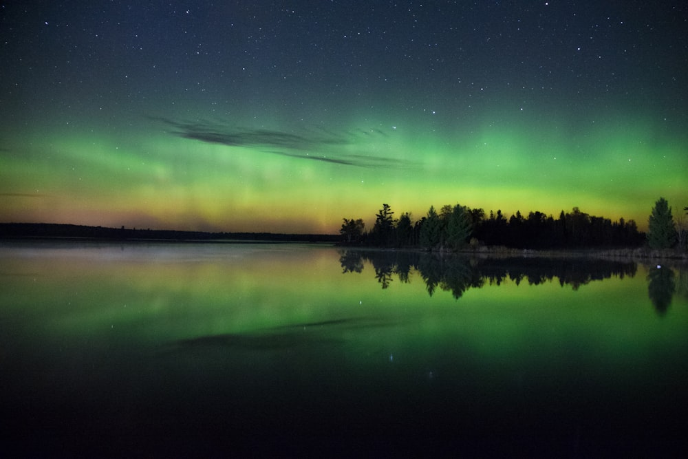 Aurora boreal verde e amarela refletida na água