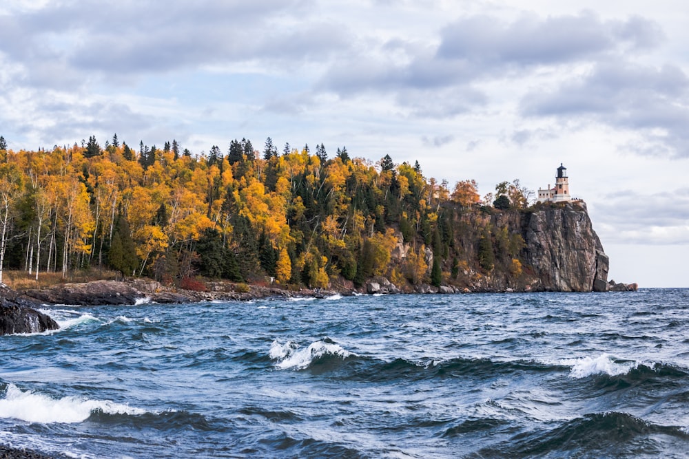 body of water near island with trees and lighthouse