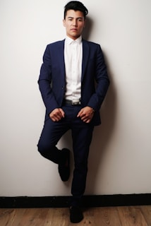 A professional man in a navy blue suit reviewing financial documents in a sleek office with silver accents.