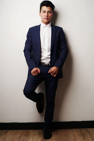 Portrait of the CEO in a sleek navy suit against a slate blue background.