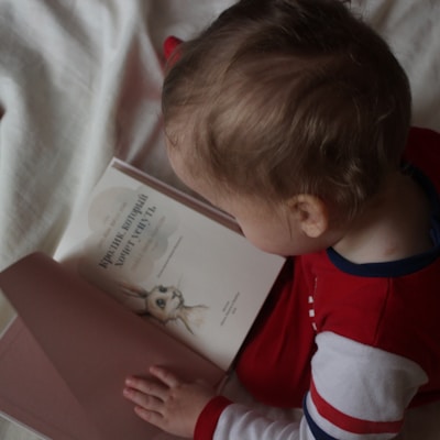 baby sitting on bed while reading on book