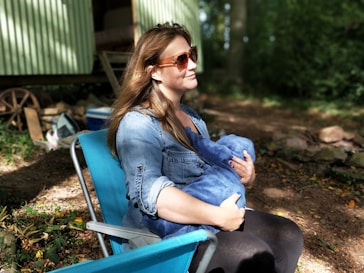 woman carrying baby while sitting on chair