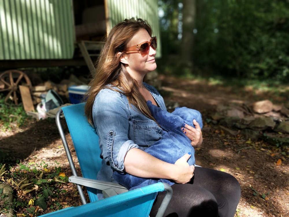 woman carrying baby while sitting on chair