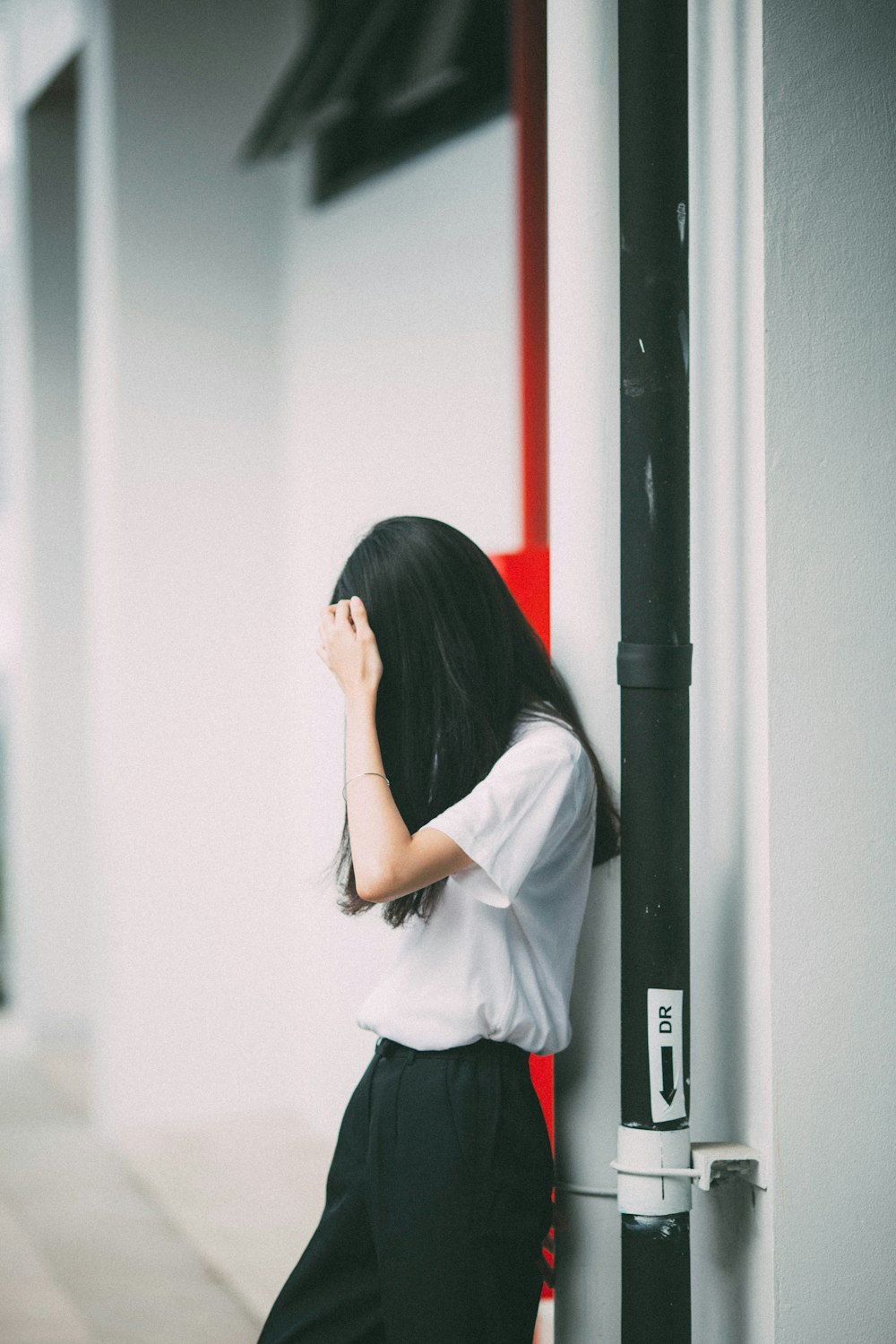 Mujer apoyada en la pared de hormigón blanco