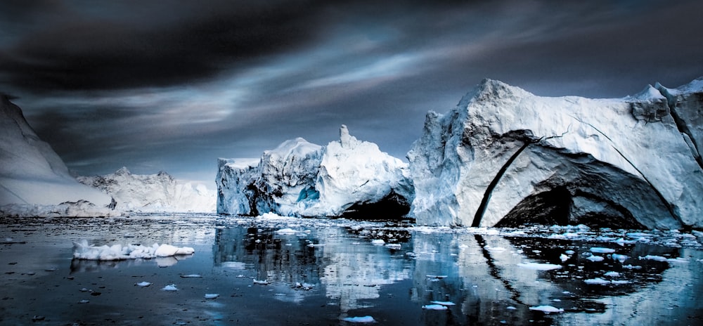 snow capped mountain near body of water under gray clouds