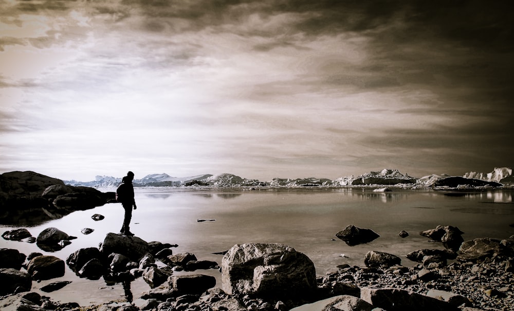 person standing on rock near body of water