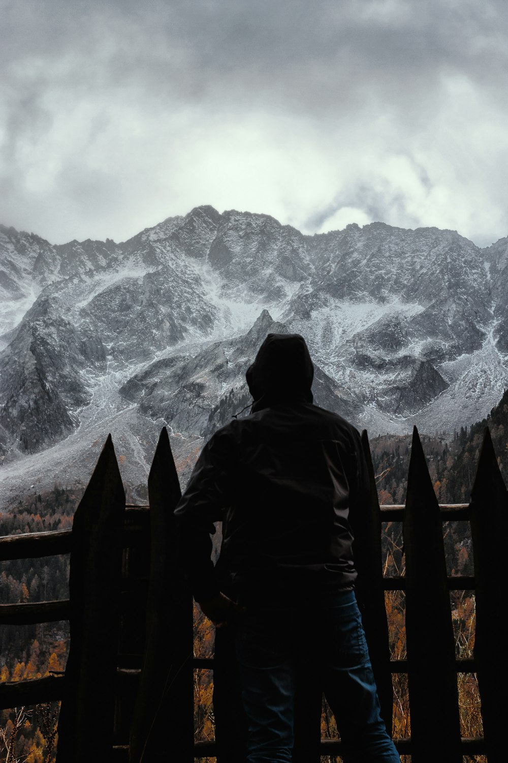 silhouette of person standing in front fence with a scene of mountains