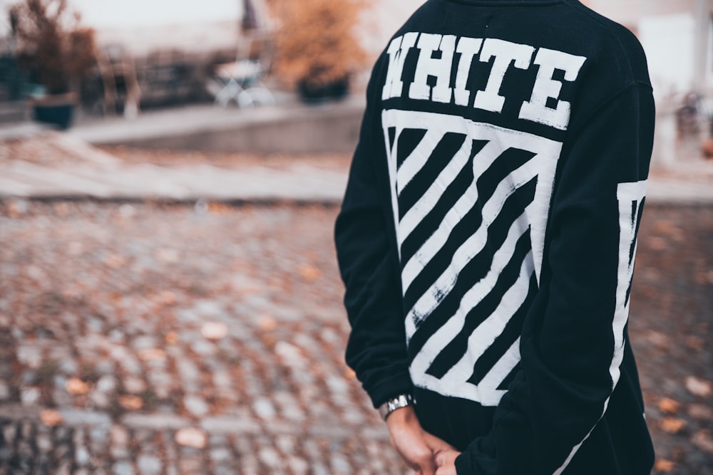 콘크리트 도로에 서 있는 흰색과 검은색 스웨터를 입은 사람