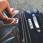 woman sitting on chair beside luggage bag