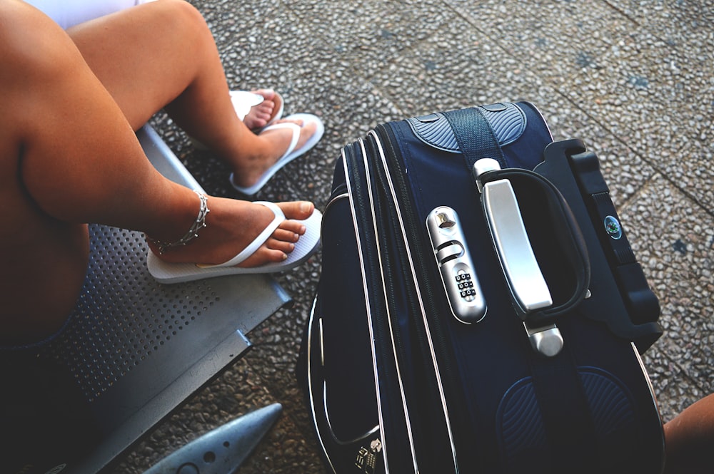 woman sitting on chair beside luggage bag