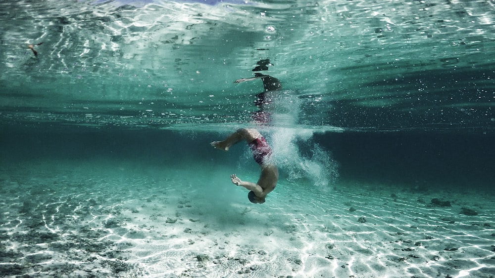 person wearing red shorts underwater