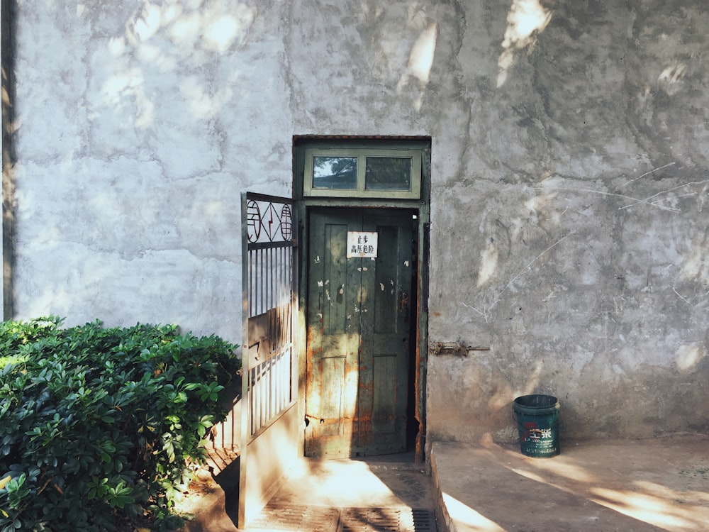 green plastic pail near wooden door