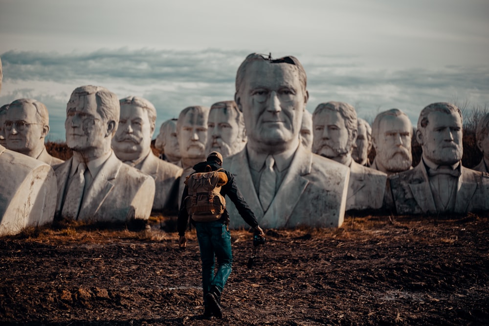 person in black hoodie walking on dirt in front of bust