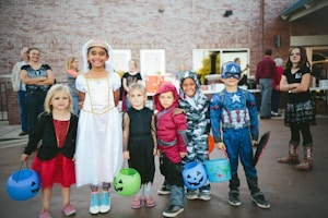 children standing while holding Jack 'o lantern and wearing costume