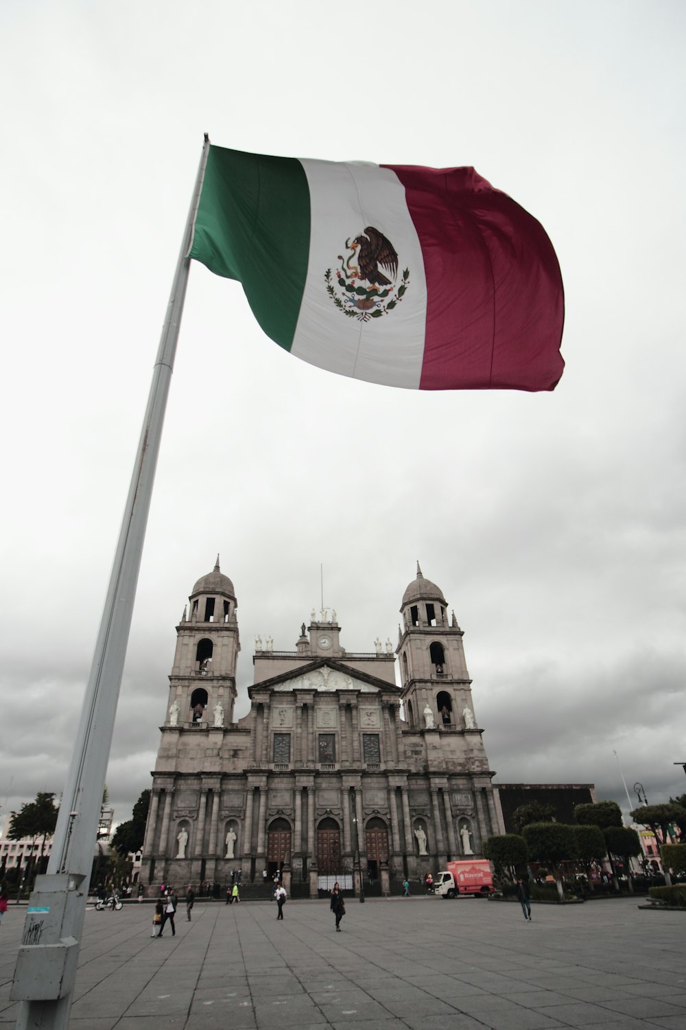 Bandera de México ondeando cerca de un edificio de concreto marrón durante el día