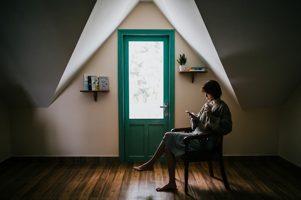 Femme assise sur une chaise à l’intérieur d’une pièce peinte en blanc