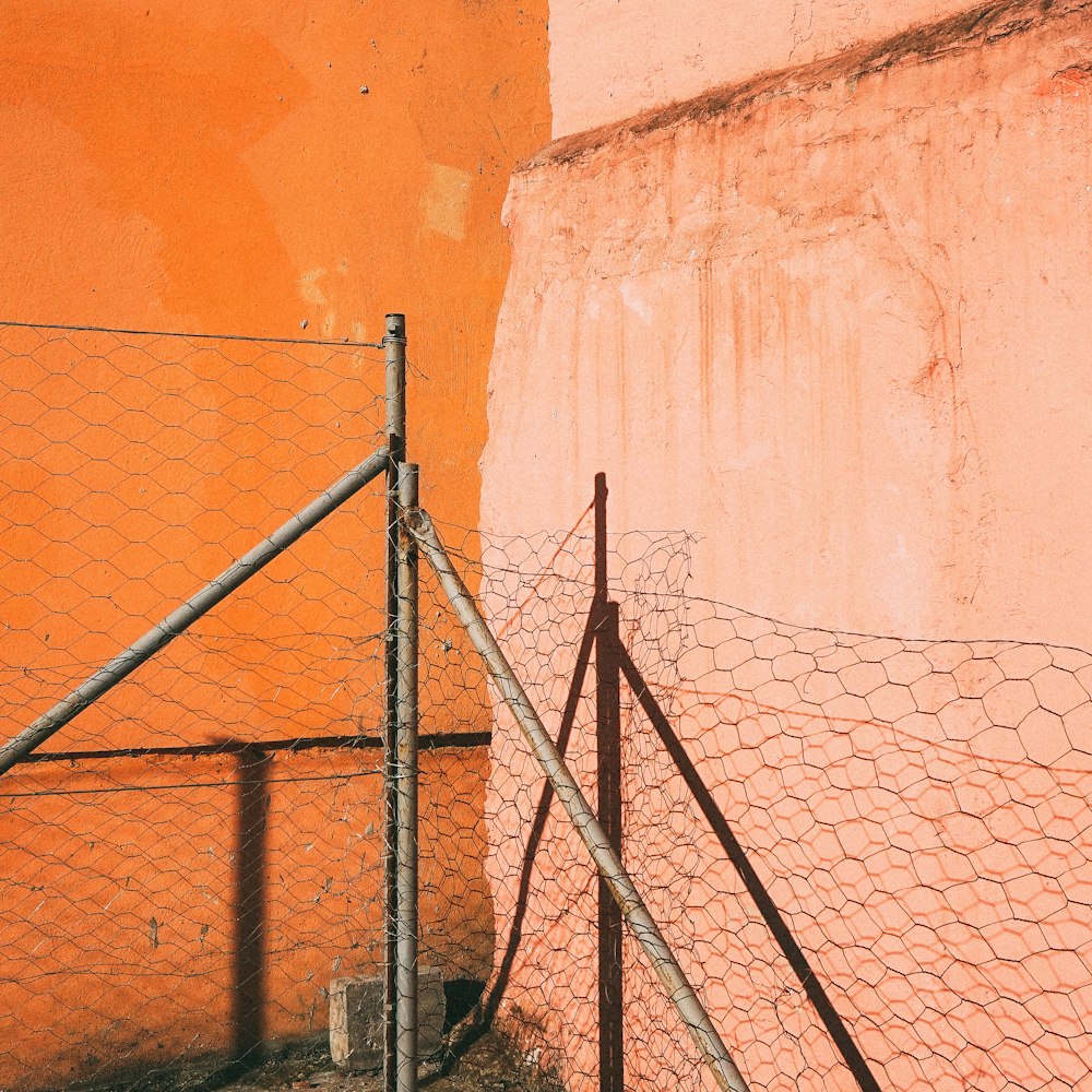 Stacheldraht auf grauen Rohren in der Nähe der orangefarbenen Wand