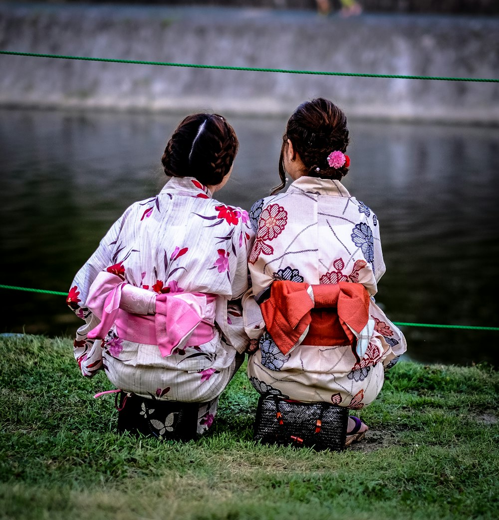 foto de duas mulheres usando quimono floral olhando para o corpo de água