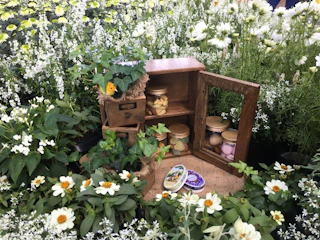 A rustic honesty box beside blooming plants in the garden.