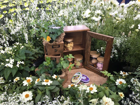 A rustic honesty box beside blooming plants in the garden.