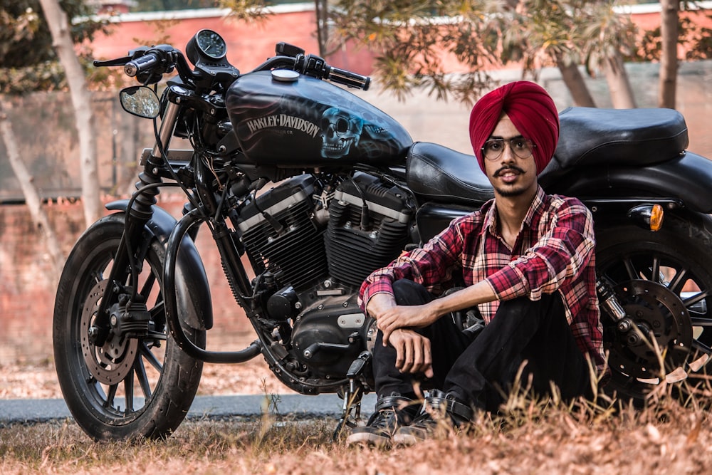 Hombre sentado al lado de la motocicleta estándar negra