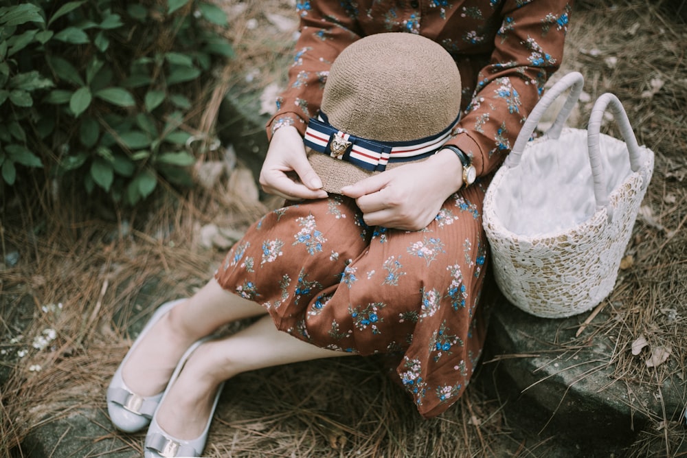 woman sitting on stone with hat on her thigh