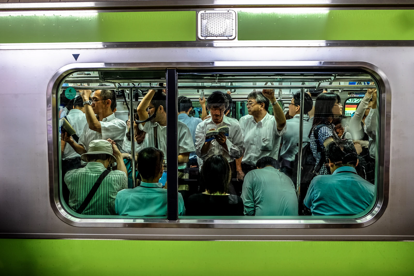 Passengers standing and sitting inside a crowded commuter train carriage