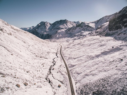 asphalt road between snow covered mountains under clear sky in Flüela Pass Switzerland