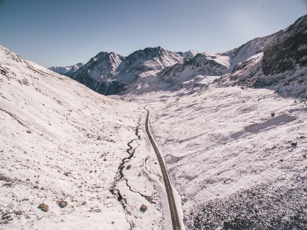 strada asfaltata tra montagne innevate sotto cielo sereno