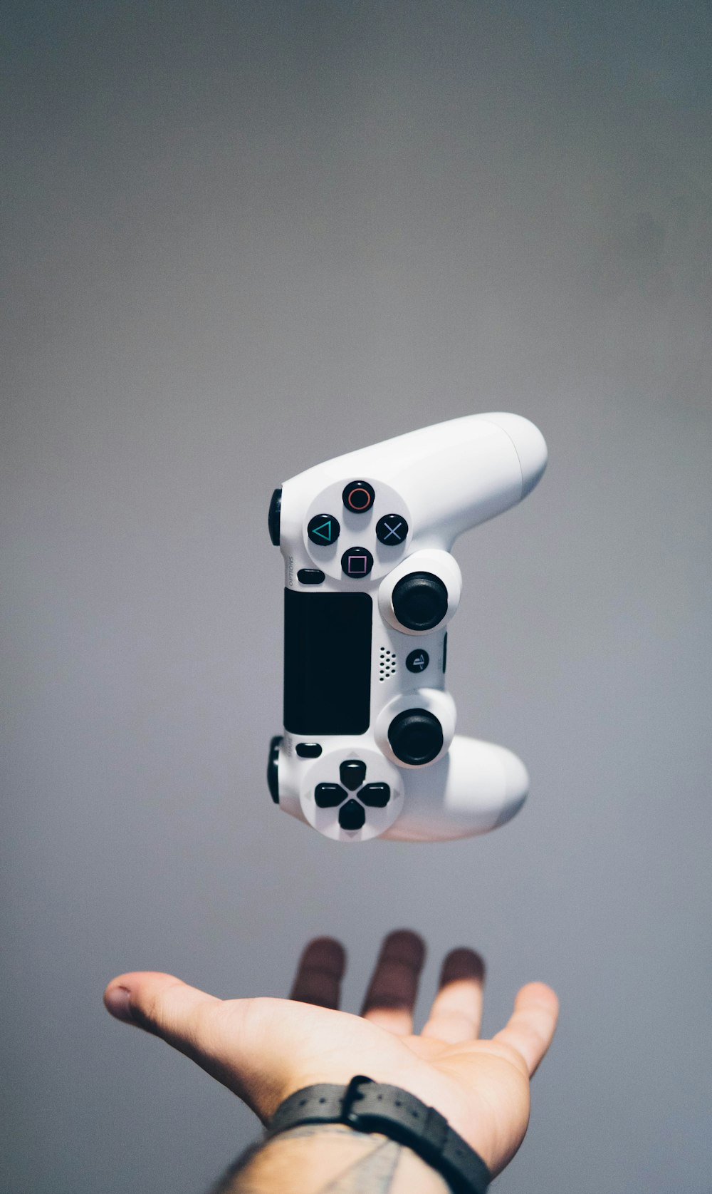 controlador Sony PS4 DualShock branco sobre a palma da mão da pessoa