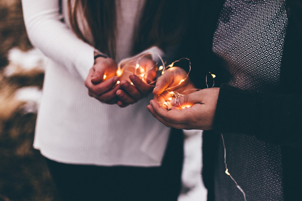 close-up photo of two person holding lighted string lights