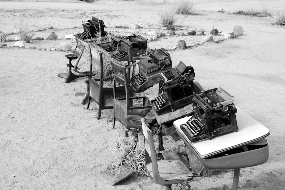 Photo en niveaux de gris d’une machine à écrire sur des tables