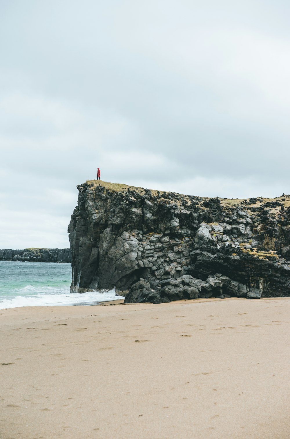 person on top of rock formation beside body of water