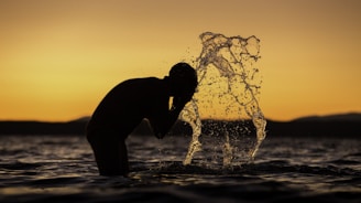 silhouette of man washing his face on body of water