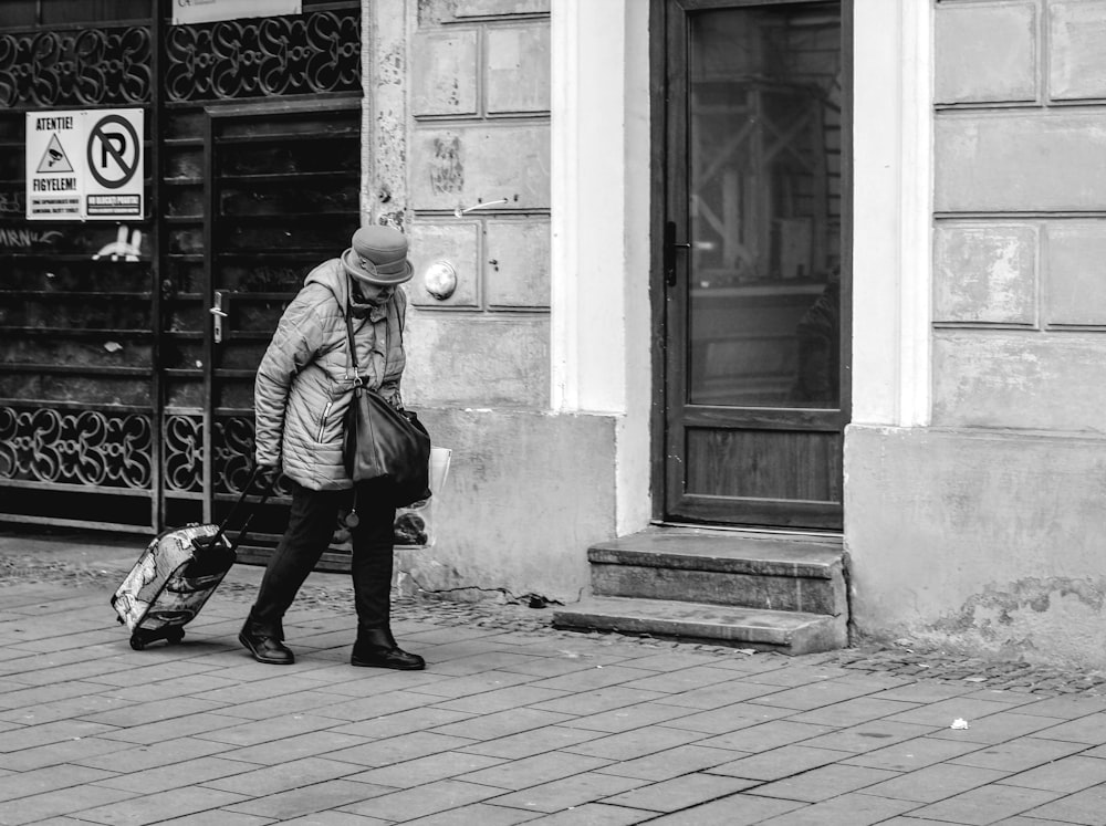 person carrying luggage walking on pathway beside building