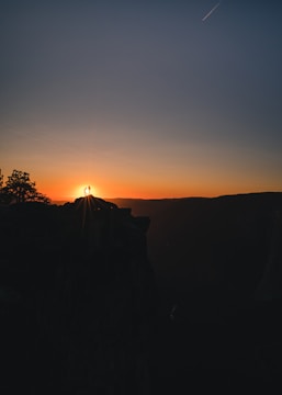A panoramic view of a couple standing on a cliff overlooking a serene beach at sunset, wrapped in warm ivory tones.