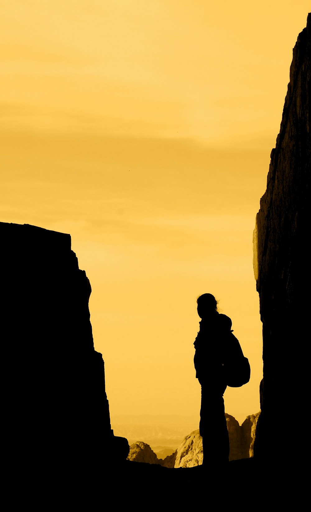 silhouette of person standing in between rocks