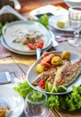 A rustic wooden table set with a perfectly grilled fish and a side of fresh greens.